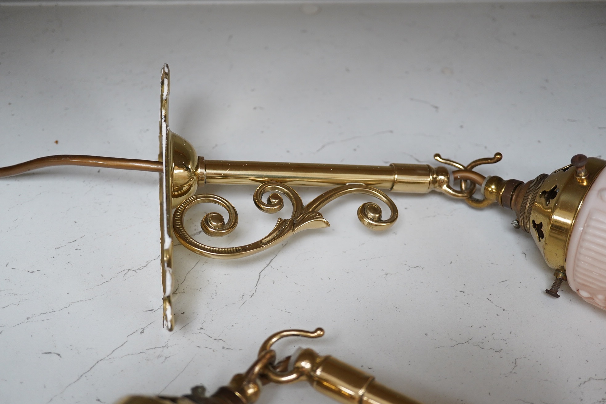A pair of French brass wall lights with opaline pink shades, decorated with bows and swags, wired, projection 23cm. Condition - good